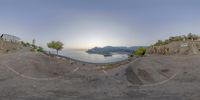 a fish eye lens showing the view of the sea in front of an island with mountains