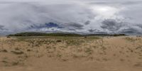 a large wide picture of a beach and some clouds and water and grass and a hill with a light blue sky