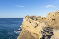 the cliffs along the coastline are steeply close to the water's edge with a few people