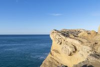 the cliffs along the coastline are steeply close to the water's edge with a few people