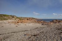 there is a lone blue object in the sand by the beach with water in the distance