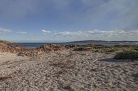 there is a lone blue object in the sand by the beach with water in the distance