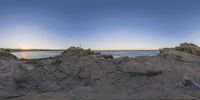 view of rocky cliff with ocean in background and sky in foreground by ocean shore