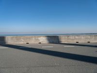 a man on a skateboard rides over a concrete barrier near the water or a shore