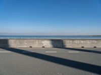 a man on a skateboard rides over a concrete barrier near the water or a shore