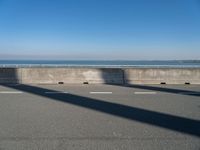 a man on a skateboard rides over a concrete barrier near the water or a shore