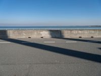 a man on a skateboard rides over a concrete barrier near the water or a shore