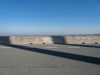 a man on a skateboard rides over a concrete barrier near the water or a shore