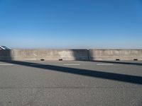 a man on a skateboard rides over a concrete barrier near the water or a shore