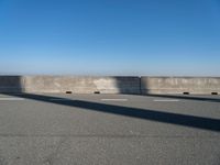 a man on a skateboard rides over a concrete barrier near the water or a shore