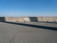 a man on a skateboard rides over a concrete barrier near the water or a shore