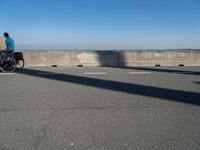 a man on a skateboard rides over a concrete barrier near the water or a shore