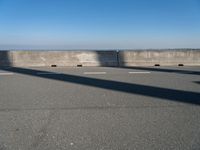 a man on a skateboard rides over a concrete barrier near the water or a shore