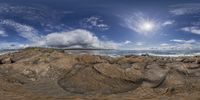 a panorama fish eye view looking down at the water from a rocky beach with rocks