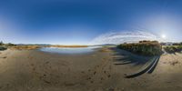 a panoramic lens image of the sun over some sand at a beach or bay