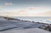 there is a wooden boardwalk that extends to the beach over a rocky hill at sunset