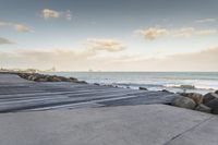 there is a wooden boardwalk that extends to the beach over a rocky hill at sunset