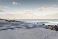 there is a wooden boardwalk that extends to the beach over a rocky hill at sunset