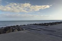 a walkway on the side of a body of water leading to an ocean on a sunny day