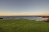 a golf course with the ocean in the background at sunset near a sandy beach with no people