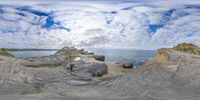 this fish eye photo shows the view from the rocks of the ocean through which you can see a beach