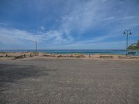 empty street in front of an ocean on a sunny day with sky and clouds above