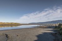 an empty beach that is next to the water with a bunch of rocks and grass