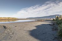 an empty beach that is next to the water with a bunch of rocks and grass