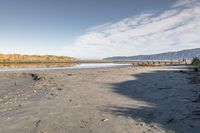 an empty beach that is next to the water with a bunch of rocks and grass