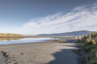 an empty beach that is next to the water with a bunch of rocks and grass