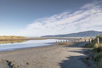 an empty beach that is next to the water with a bunch of rocks and grass