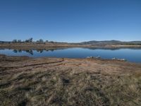 large pond with lots of water and brown land in the background with hills and blue sky above