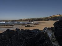 a beach area with several large rocks and water surrounding it and the water crashing over the shore