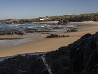 a beach area with several large rocks and water surrounding it and the water crashing over the shore