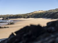 an image of the coast with a black rocks in front of it and water behind