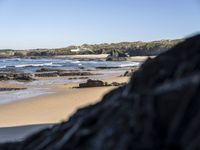 an image of the coast with a black rocks in front of it and water behind