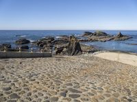 an old beach on the shores of the ocean with a stone path leading to rocks and water