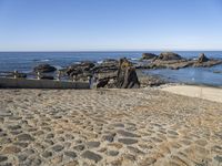 an old beach on the shores of the ocean with a stone path leading to rocks and water