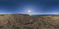 the beach has been eroded into a hill, with the sun shining in the distance