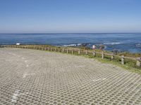 a brick walkway next to the ocean with a seagull on top of it