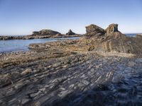 a large rock formation near the ocean on a sunny day at porth d'alife