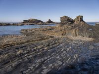 a large rock formation near the ocean on a sunny day at porth d'alife