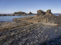 a large rock formation near the ocean on a sunny day at porth d'alife