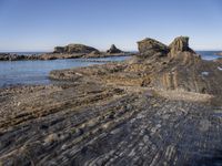 a large rock formation near the ocean on a sunny day at porth d'alife