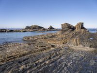 a large rock formation near the ocean on a sunny day at porth d'alife