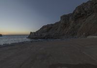 there are rocks and the water by the beach at sunset time at this area of town