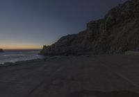 there are rocks and the water by the beach at sunset time at this area of town