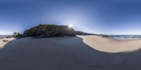 an image of beach area at sunset with a bright blue sky above the hill and ocean below