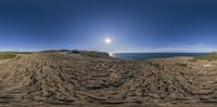 the beach has been eroded into a hill, with the sun shining in the distance