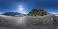 a 360 degree lens shot shows an empty road, mountains, and the sun in the background